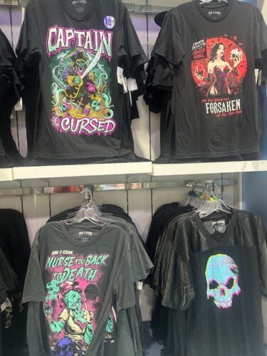 Black graphic shirts featuring Captain of the Cursed, Crimson Lounge, Nurse You Back to Death, and a colorful skull.
